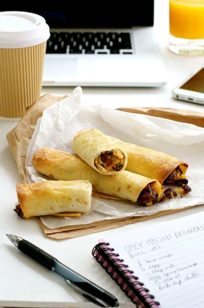 Spicy Italian Breakfast Roll Ups on a work desk with takeaway coffee cup, computer and notebook