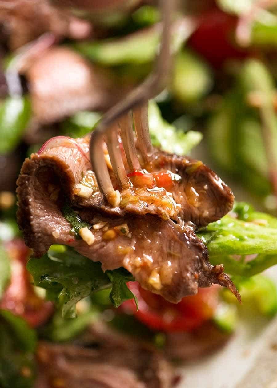 Fork stabbing piece of beef in Thai Beef Salad