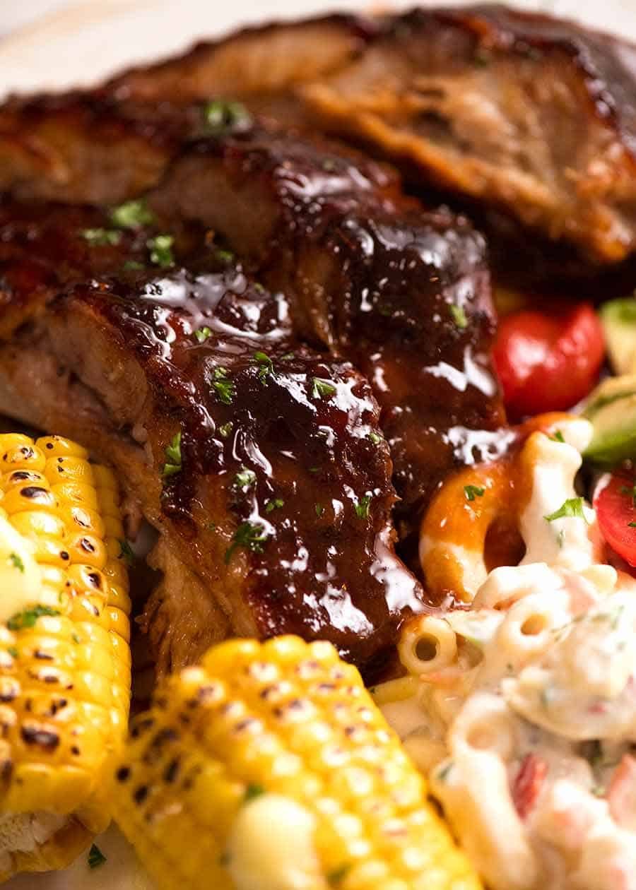 Close up of Oven Barbecue Pork Ribs dinner with a side of Macaroni Salad, corn and cucumber tomato salad
