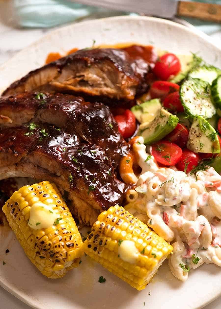 Oven Barbecue Pork Ribs dinner with a side of Macaroni Salad, corn and cucumber tomato salad