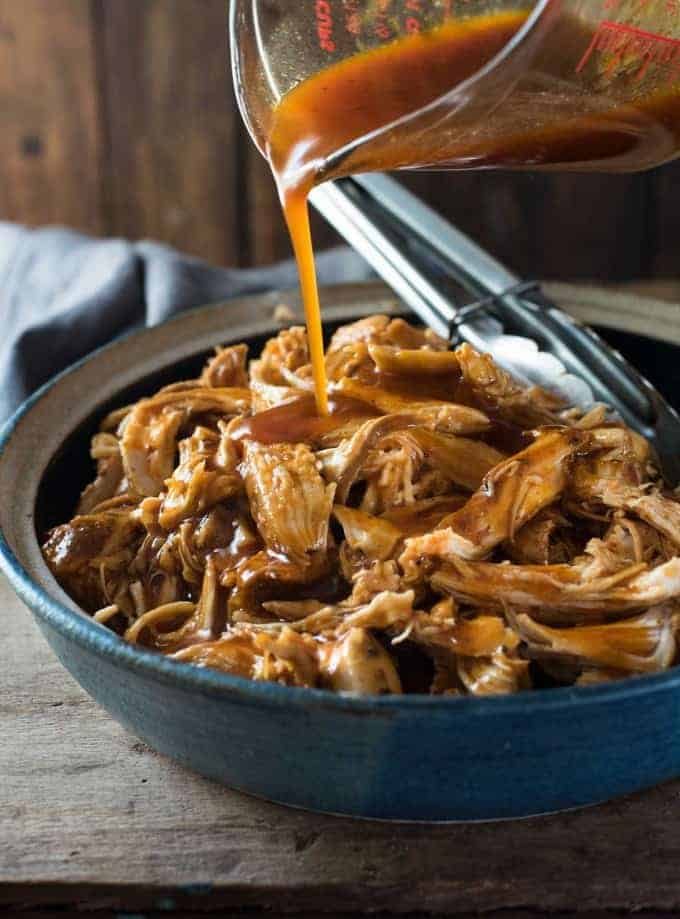 Pouring Honey Buffalo sauce over chicken