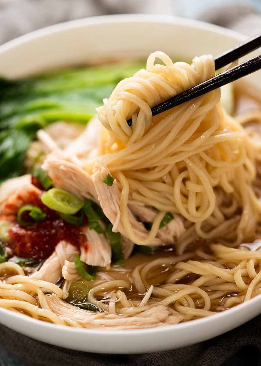 Chopsticks picking up noodles in an Asian noodle soup