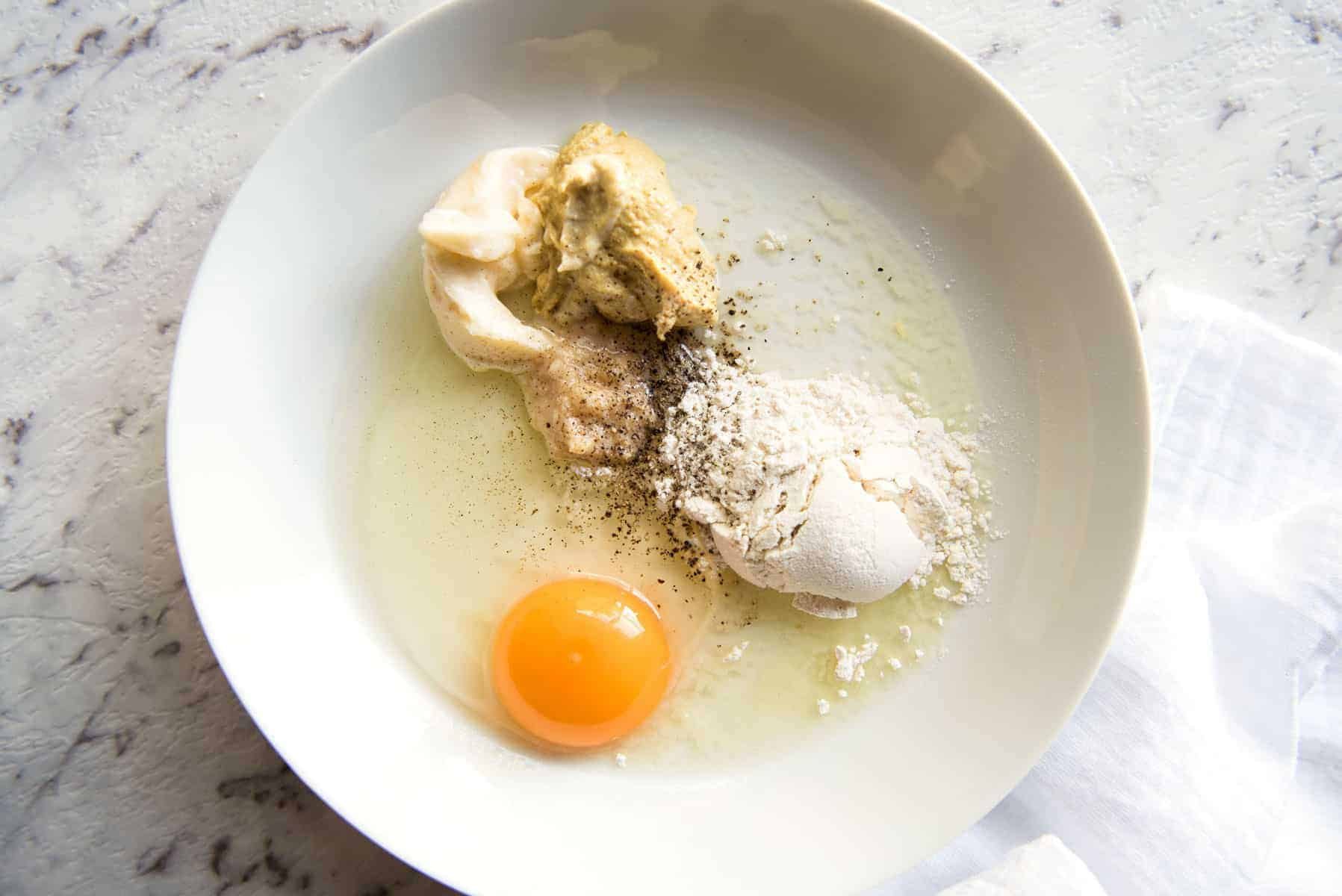 A bowl with the ingredients for the dredging mixture to coat chicken in breadcrumbs.