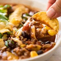 Close up of corn chip being dunked into Taco Soup