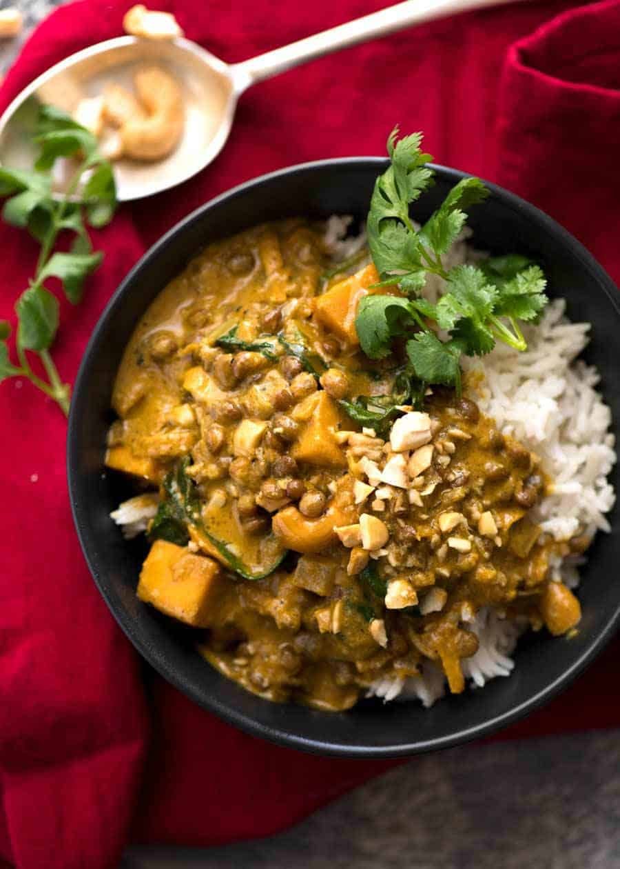 Coconut Curry with Lentils & Pumpkin served over rice in a small black bowl, ready to be eaten.