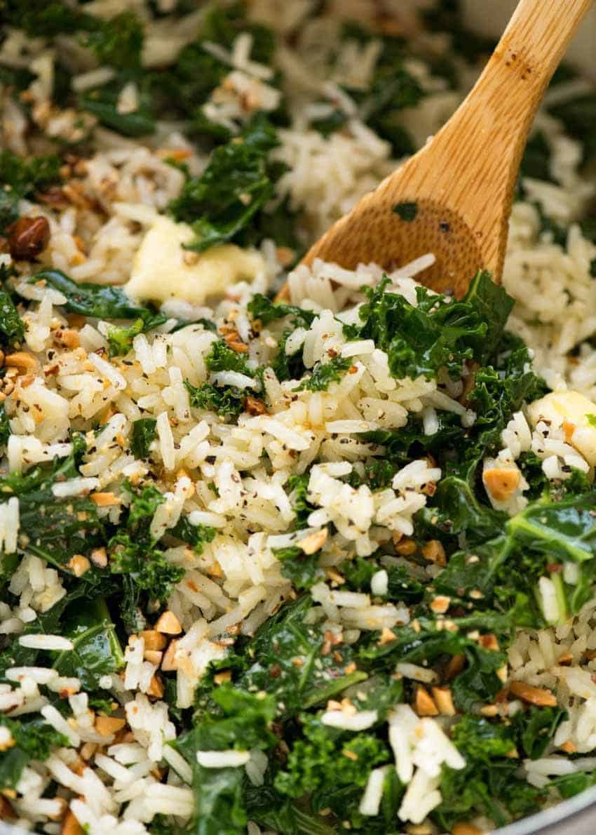 Close up of Garlic Butter Rice with Kale recipe in a pot with a wooden spoon, fresh off the stove ready to be served.