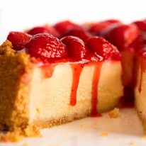 Close up of slice of Strawberry Cheesecake with Strawberry Sauce dripping down the side
