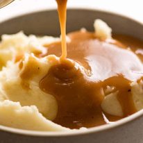 Pouring gravy over mashed potato