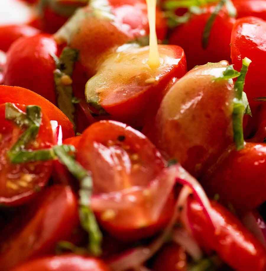 Dressing being poured over Tomato Salad