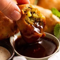 Dipping Samosa into tamarind sauce